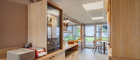 Una cocina moderna con armarios de madera, un refrigerador y una ventana con vistas a un jardín.