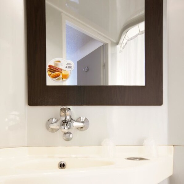 A bathroom with a white sink, a mirror with a dark frame, and a towel rack. - Premiere Classe Besancon - Ecole Valentin (Ecole-Valentin)