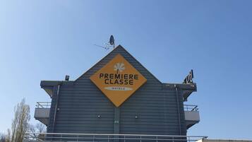 Un edificio con una targa a forma di rombo giallo che recita 'Premiere Classe Hotels'.