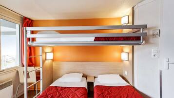 A compact hotel room with two single beds, a bunk bed, a desk, and a chair.
