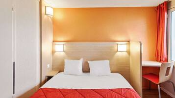 Ein Hotelzimmer mit einem Bett, zwei Nachttischlampen, einem Schreibtisch und einem Sessel.