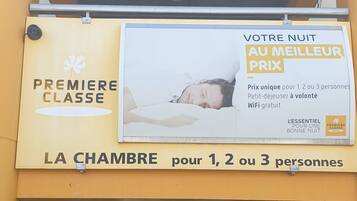 L’entrée d’un hôtel, avec une affiche annonçant un forfait pour une, deux ou trois personnes, comprenant le Wi-Fi et un court séjour.