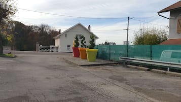 Una calle residencial con una casa, una valla verde y macetas coloridas.