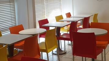 A dining area with round tables and chairs in red, yellow, and orange colors.