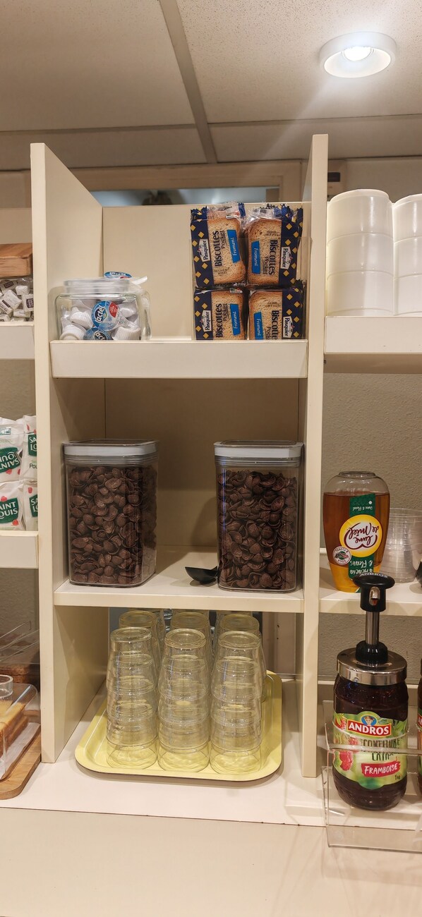 A shelf with jars of cookies, a jar of jam, and a dispenser.