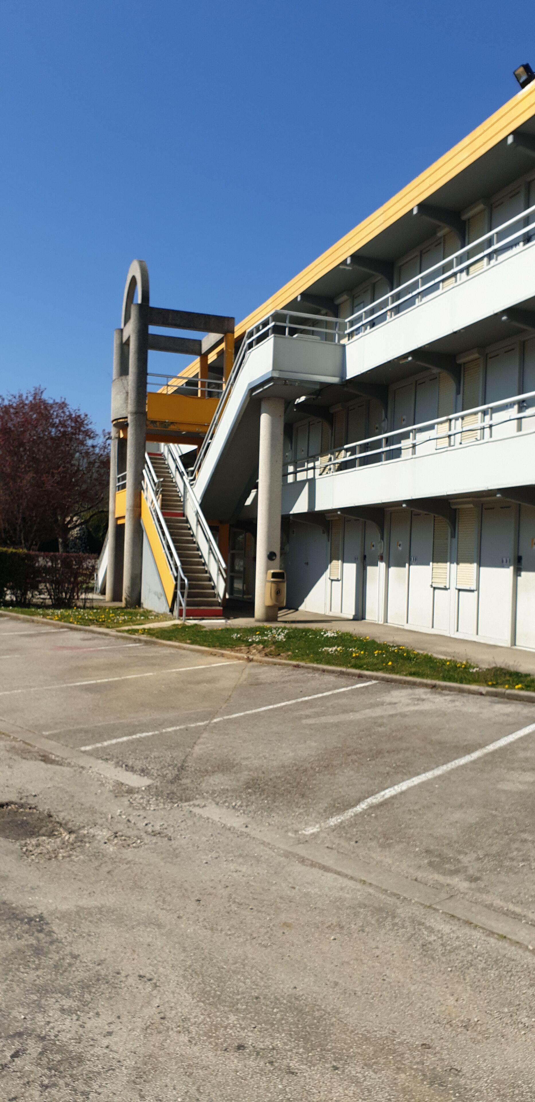 A multi-story building with a central staircase and a yellow and white color scheme.