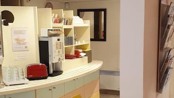 A restaurant with colorful chairs and tables, a counter with a coffee machine, and shelves with food items.