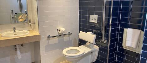 A modern bathroom with a white sink, a toilet, and a shower area.