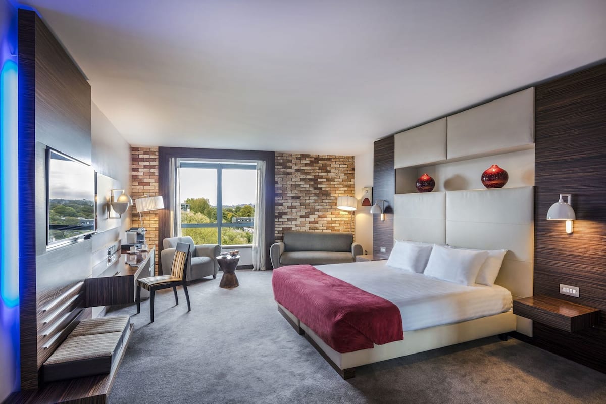 Ett modernt hotellrum med en stor säng, ett skrivbord och utsikt över omgivningarna.