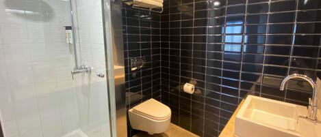 A modern bathroom with a glass-enclosed shower, a white toilet, and a sink with a mirror.
