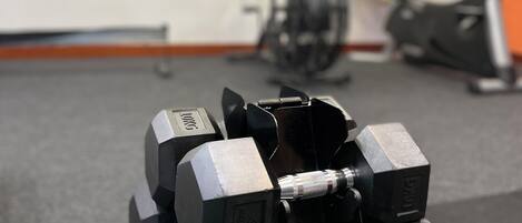 Un gimnasio con mancuernas, una bicicleta estática y una bicicleta de ejercicio.