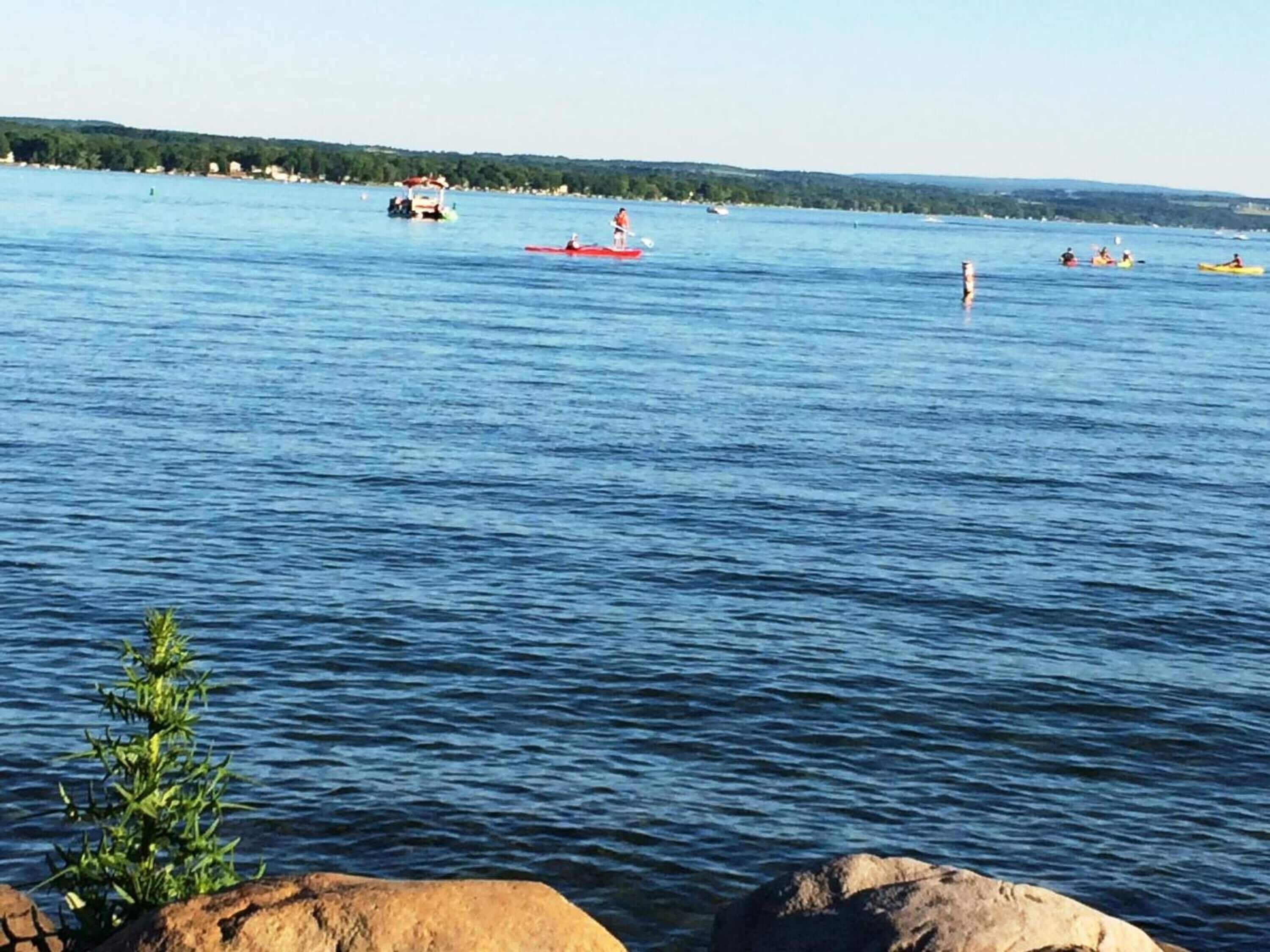 A calm lake with kayaks and a small boat.