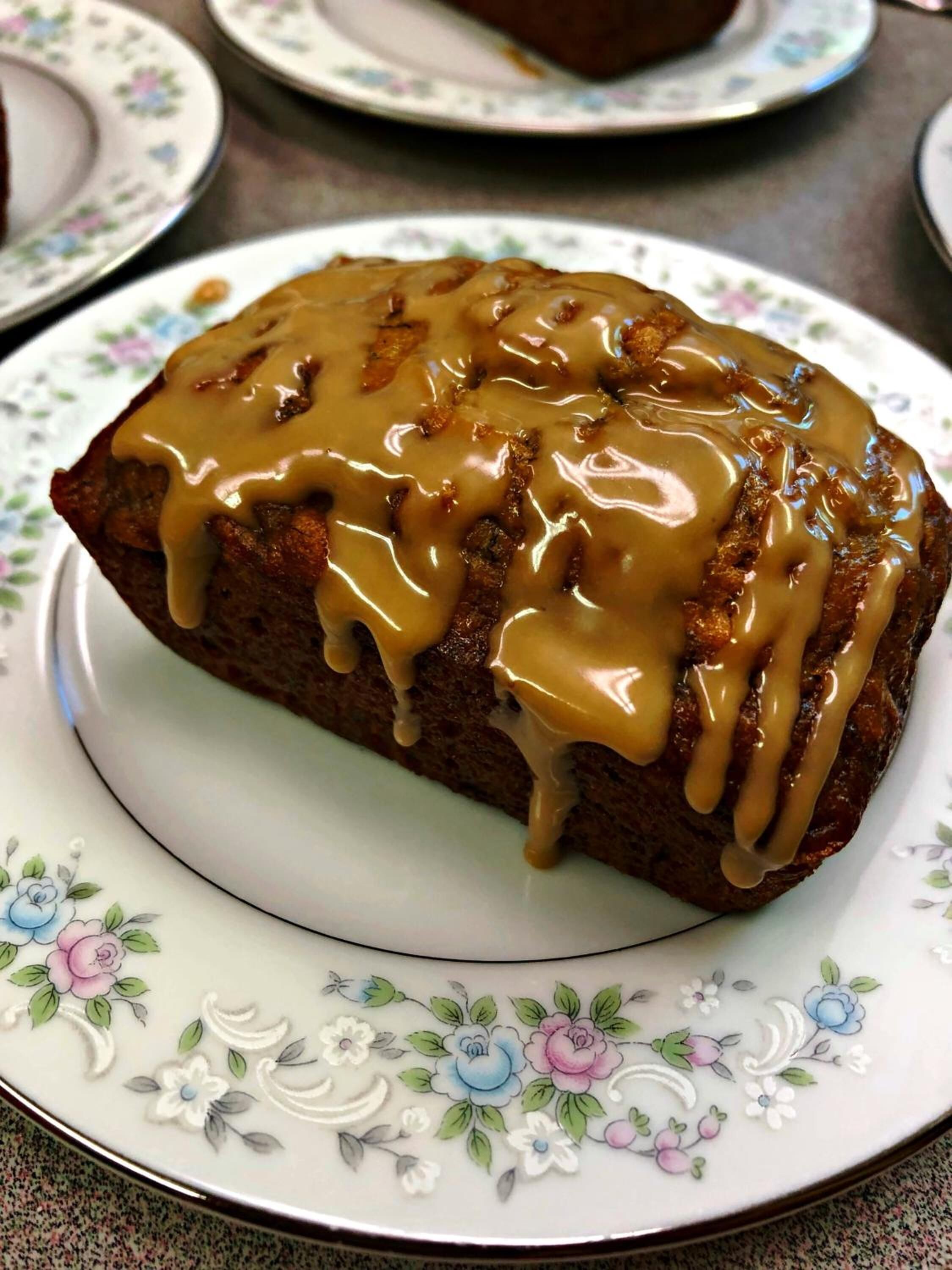 A slice of bread with caramel sauce on a floral plate.