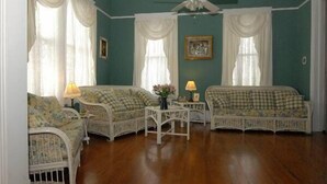 A room with two wicker sofas, a small table with a vase, and a ceiling fan.
