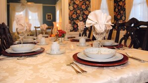 A dining table set with white plates, red and gold cutlery, and a centerpiece with folded napkins.