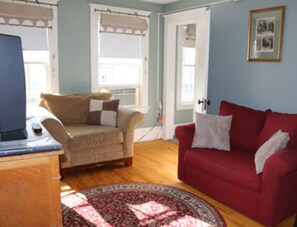 A living room with a beige sofa, a red sofa, a wooden coffee table, and a patterned rug.