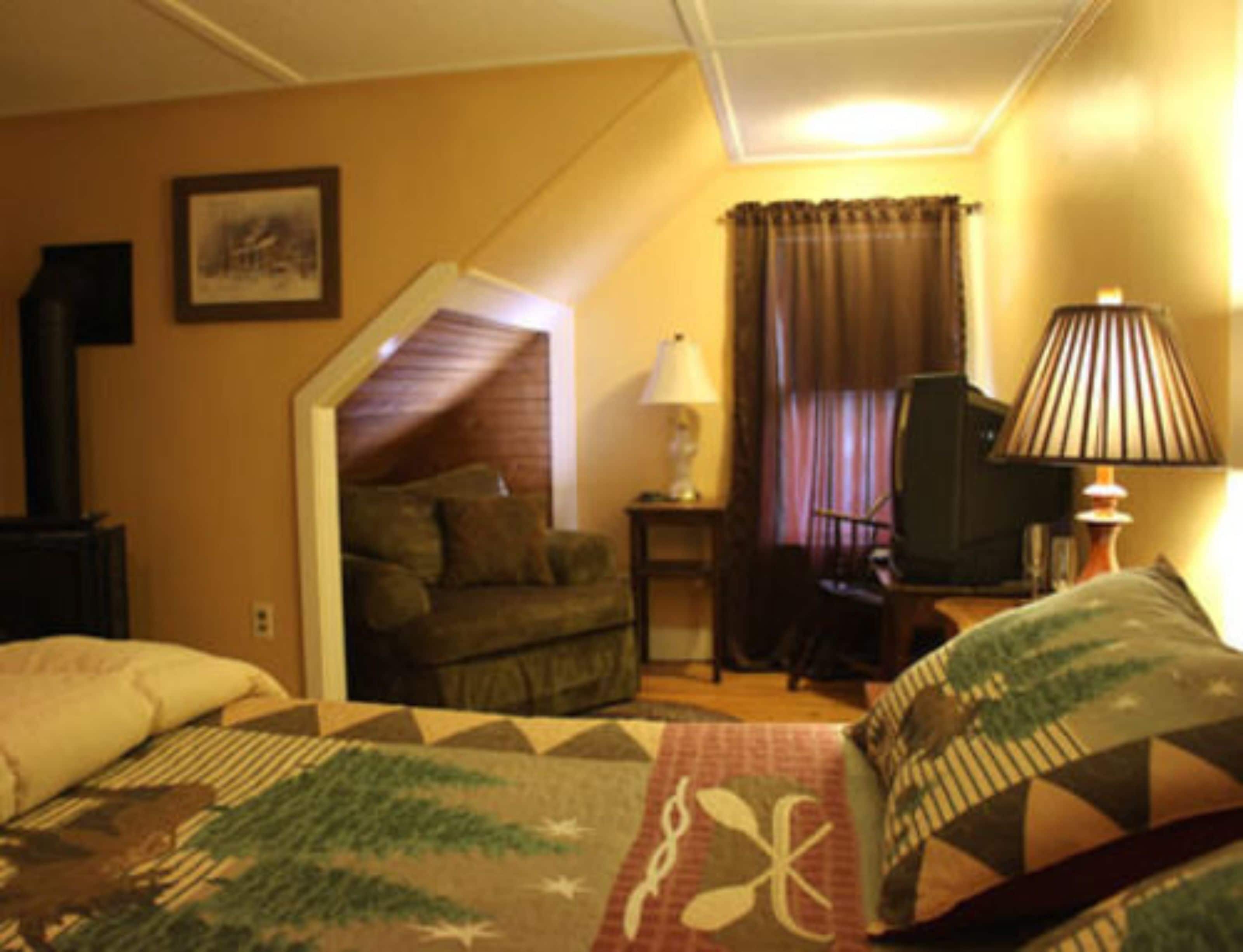 A cozy room with a bed, a chair, a lamp, and a television.