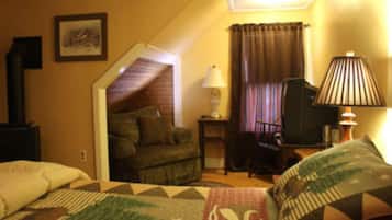 A cozy room with a bed, a chair, a lamp, and a television.