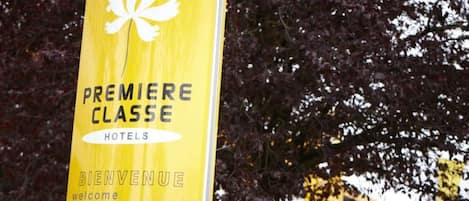 Un letrero amarillo con el texto 'PREMIERE CLASSE HOTELS' y 'BIENVENUE' en varios idiomas.