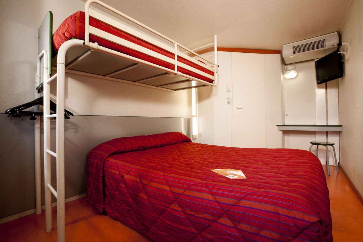 A bunk bed room with a desk and chair, a heater, and a television.