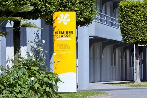 Un panneau jaune indiquant un hôtel, avec les inscriptions « HÔTELS DE PREMIÈRE CLASSE » et « BONNE ROUTE ».