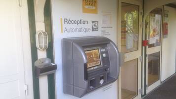 A reception area with an automated machine, a sign for Premier Classe Hotels, and a glass door entrance.