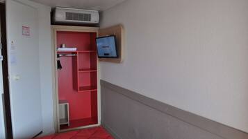 Een hotelkamer met een rood bed, een rode kledingkast, een televisie aan de muur en een airconditioning.