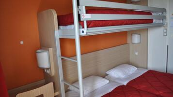 Un lit superposé avec une couverture rouge, un oreiller blanc et une tête de lit en bois.