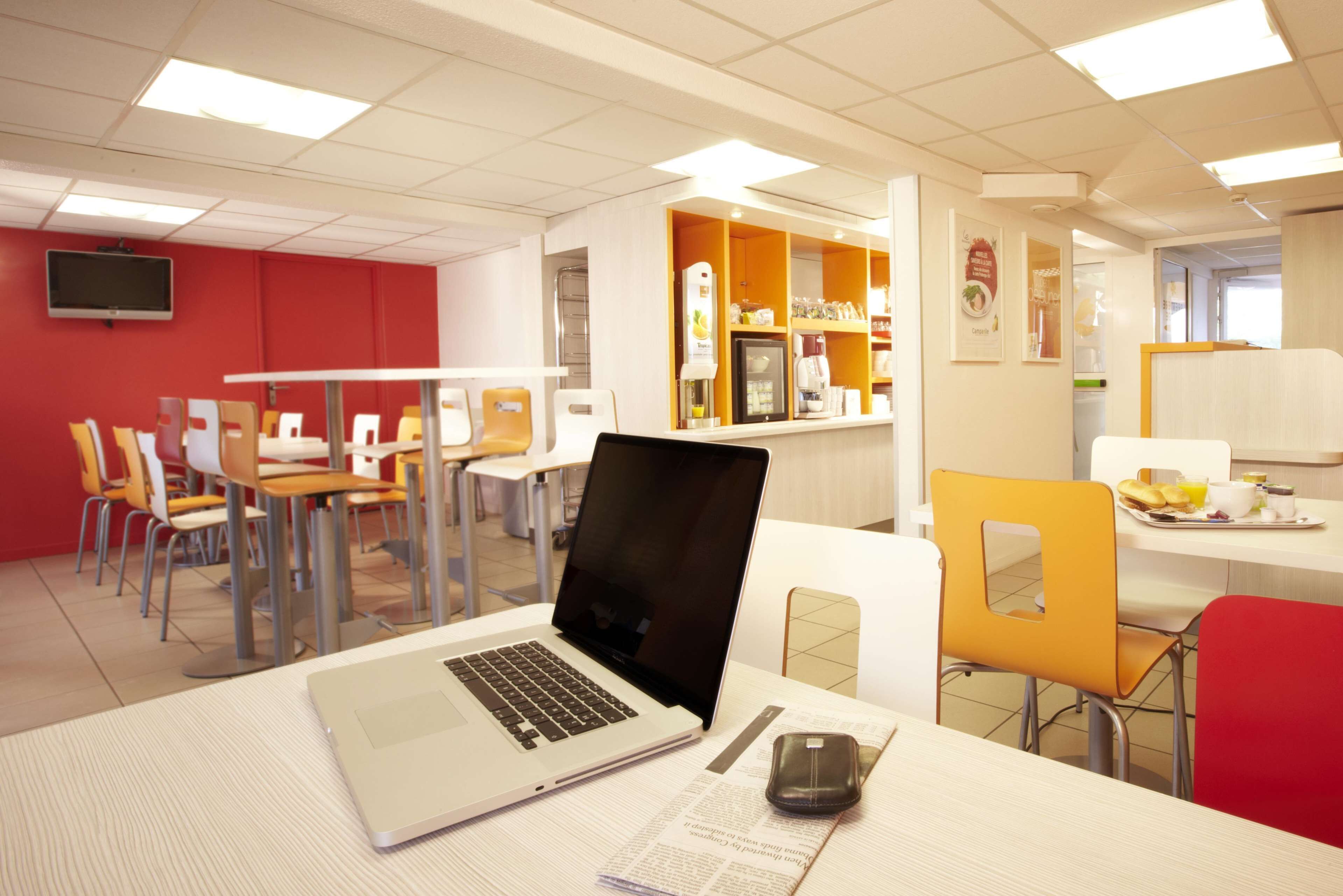 A modern dining area with tables, chairs, and a laptop on one table.