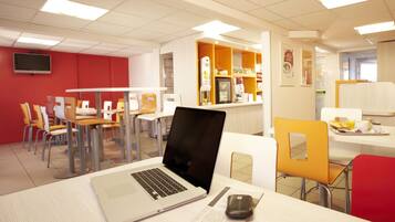 A modern dining area with tables, chairs, and a laptop on one table.