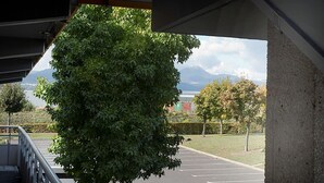 A parking area with a tree in the foreground and a view of mountains in the background. - PREMIERE CLASSE CLERMONT FERRAND SUD - Aubière (Aubiere)