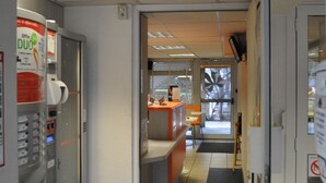 A hallway with vending machines, a reception desk, and a door leading to another room. - PREMIERE CLASSE CLERMONT FERRAND SUD - Aubière (Aubiere)