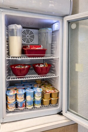 Un réfrigérateur dont les étagères sont remplies de divers aliments, notamment des yaourts et des boîtes.