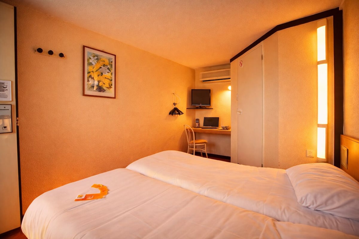 Een hotelkamer met een bed, een bureau, een stoel, een televisie en een kledingkast.