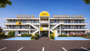Un hôtel à deux étages, doté d’une entrée principale et d’un parking avec des places délimitées.