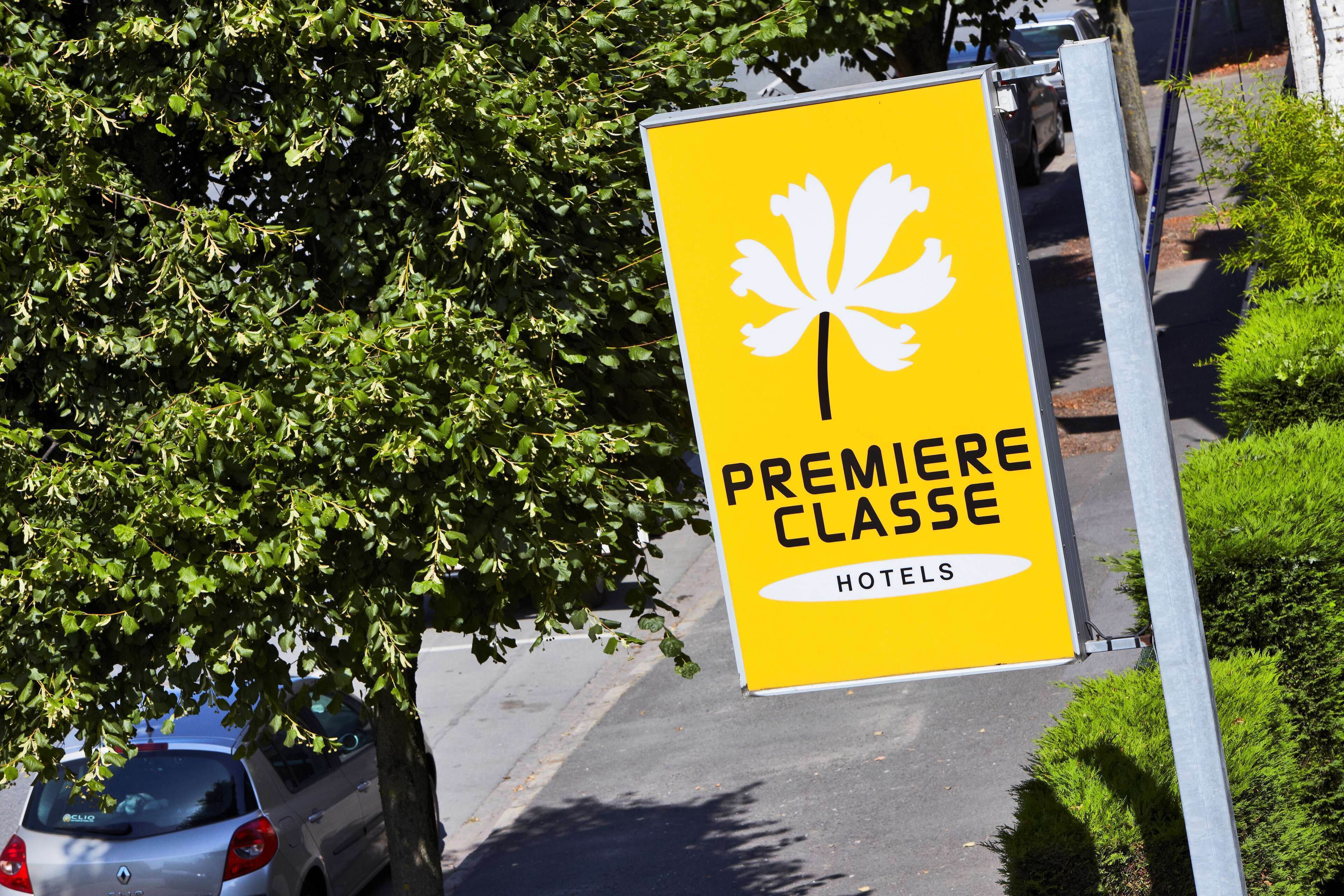 A yellow sign with a white fleur-de-lis symbol and the text "PREMIERE CLASSE HOTELS" on a metal pole.