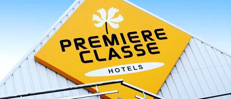 Una señal amarilla con la leyenda 'Premiere Classe Hotels' y un logotipo de hoja de arce.