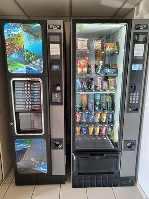 Two vending machines with a selection of snacks and beverages. - Premiere Classe La Rochelle Sud-Angoulins (Angoulins)