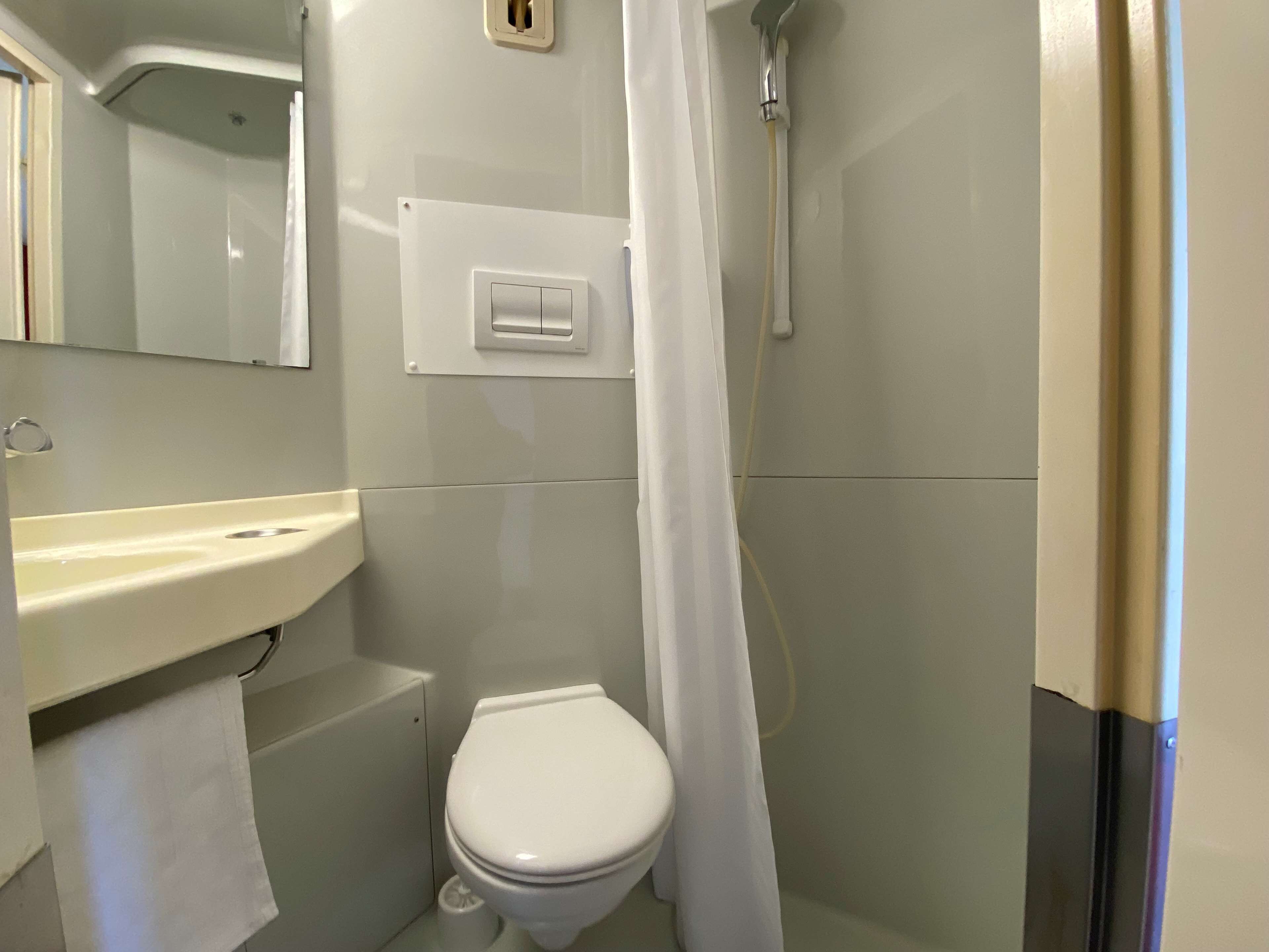 Un baño pequeño y limpio con inodoro, lavabo y ducha.
