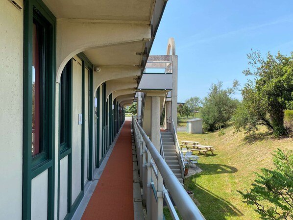 A covered walkway with a red carpet, outdoor seating, and a staircase leading to a higher level. - Premiere Classe La Rochelle Sud-Angoulins (Angoulins)