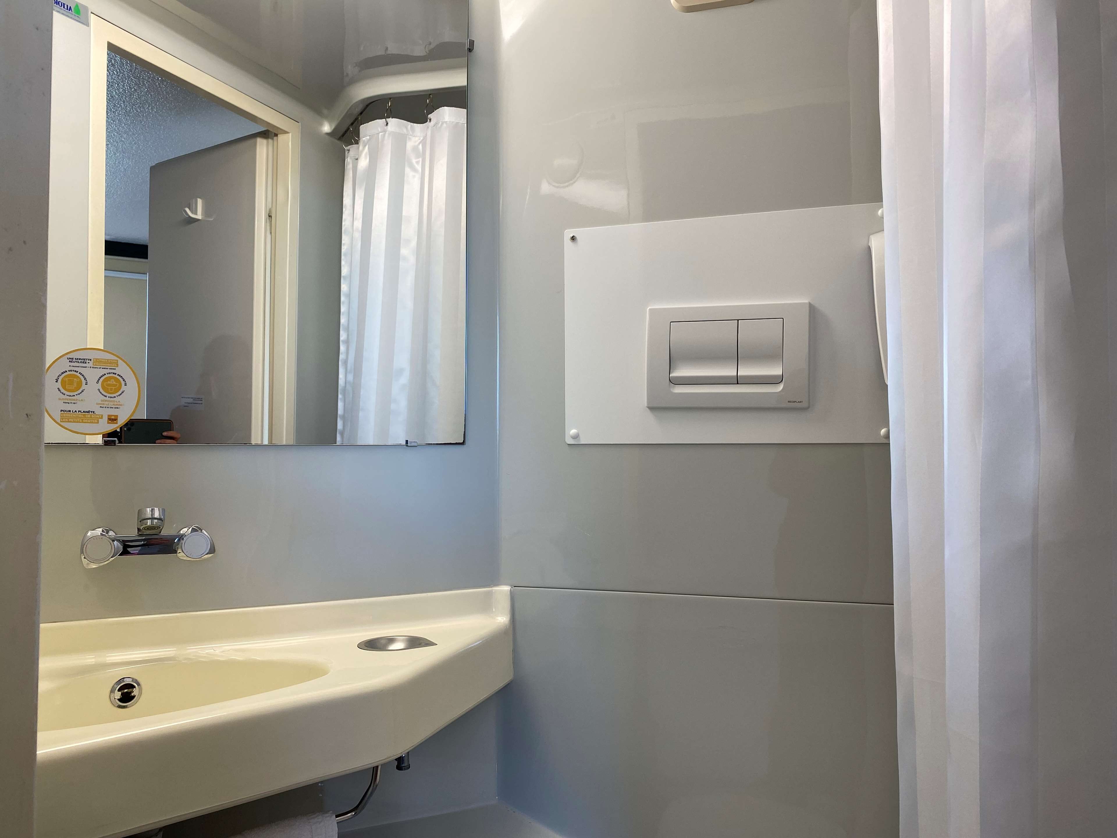 A bathroom with a sink, mirror, and a light switch.