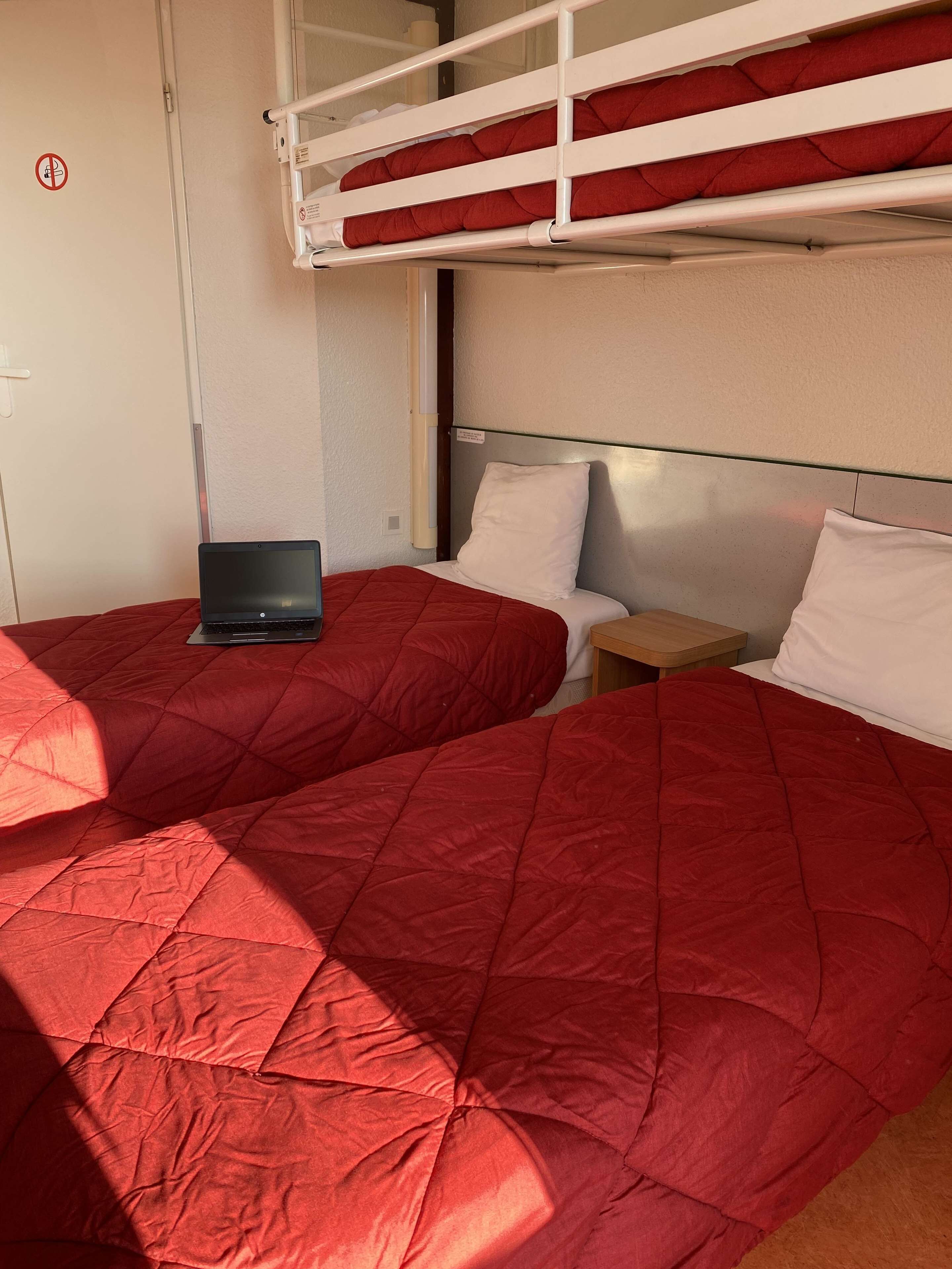 A bunk bed room with a laptop on one bed and a small table with a pillow on the other.