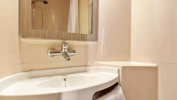Une salle de bain avec un lavabo blanc, un miroir et une douche.