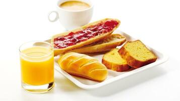 Bandeja de desayuno con un hot dog, dos rebanadas de pan, un croissant y un vaso de jugo de naranja.