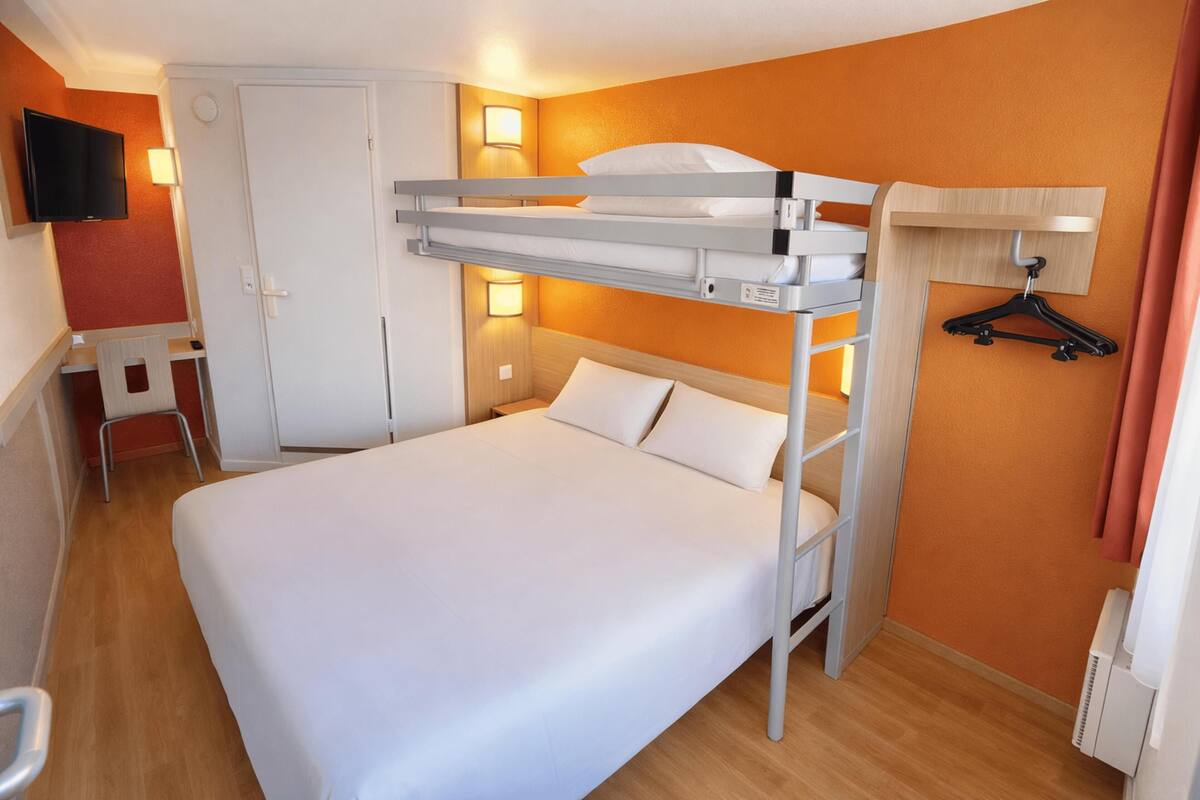 Habitación con literas, televisión, lámpara de noche y escritorio.