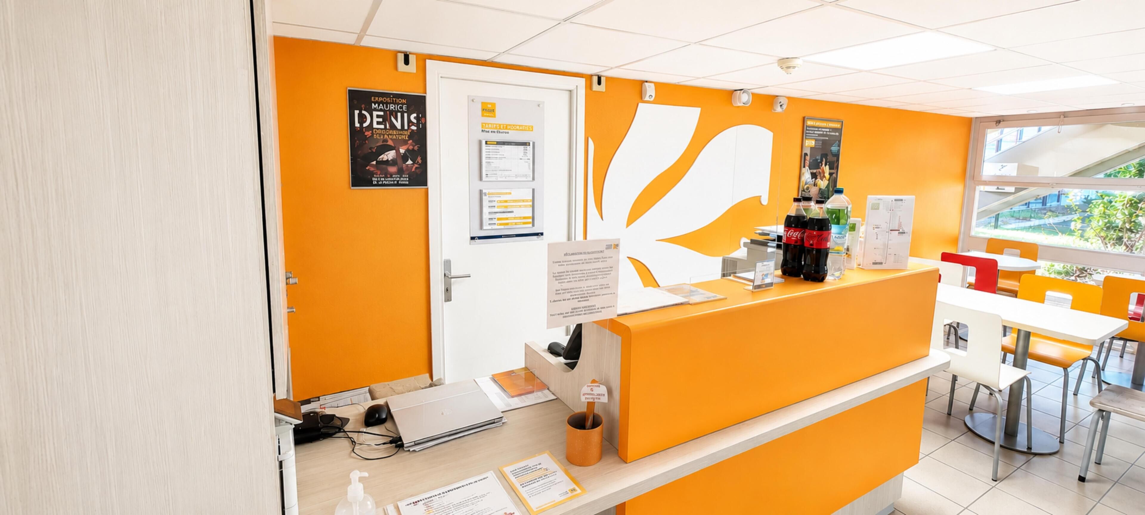 Een receptiegedeelte met een balie, stoelen, een computer en informatieposters aan de muur.