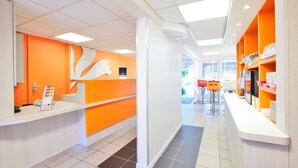 Una zona de recepción moderna con una decoración en tonos naranja brillante, un mostrador de recepción blanco y vistas al área de estar exterior.