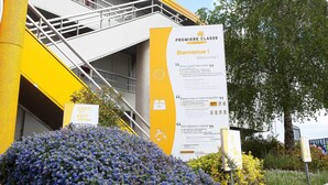 Un edificio con fachada amarilla, una escalera y un cartel con texto.