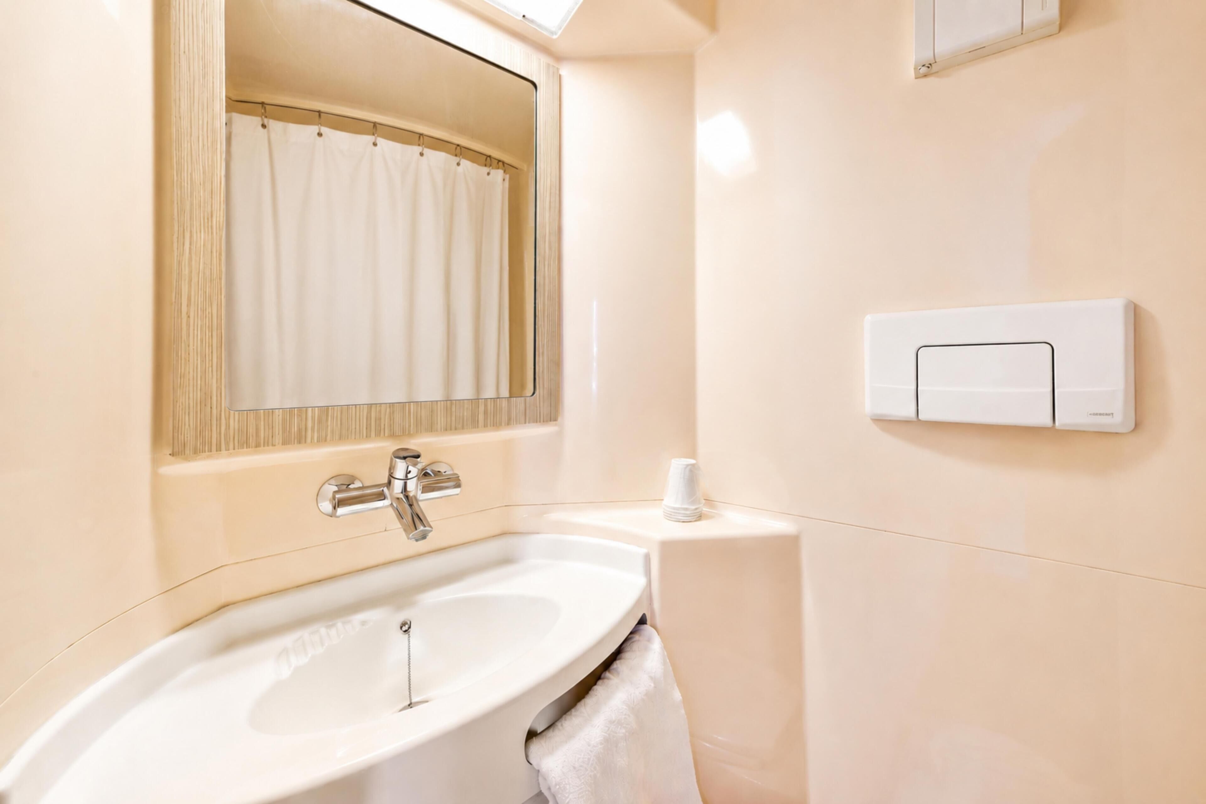 Un baño con lavamanos, espejo, toalla y soporte para papel higiénico.