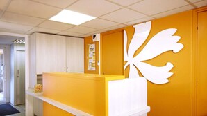 Una zona de recepción con un mostrador amarillo y un elemento decorativo blanco en la pared.